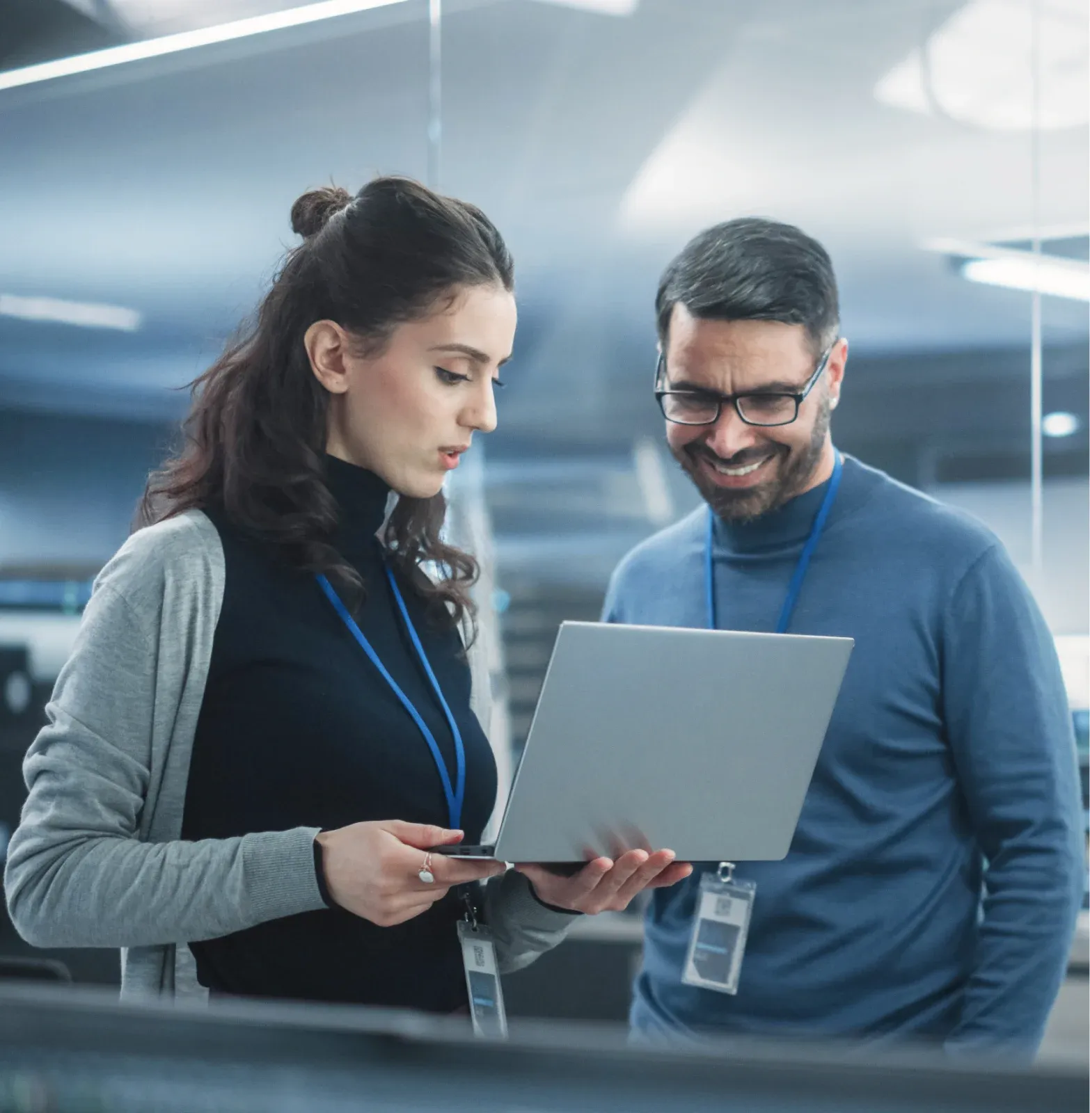 Two colleagues chatting in front of a laptop in a modern environment, probably a data center.