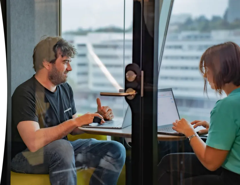 A smiling man wearing an Infomaniak T-shirt handles the migration of a customer sitting opposite him