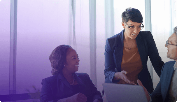 Image of three professionals talking over a computer in a bright office, symbolising collaboration and consultation in the legal sector.