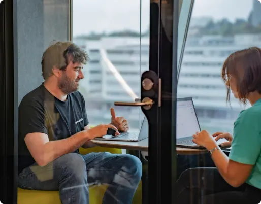 A smiling man wearing an Infomaniak T-shirt handles the migration of a customer sitting opposite him